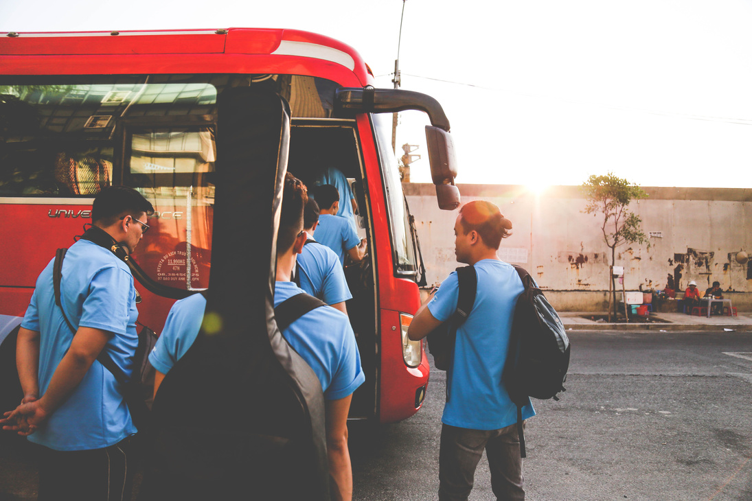 Group of Men Wearing Blue Shirts About to Enter Red Bus